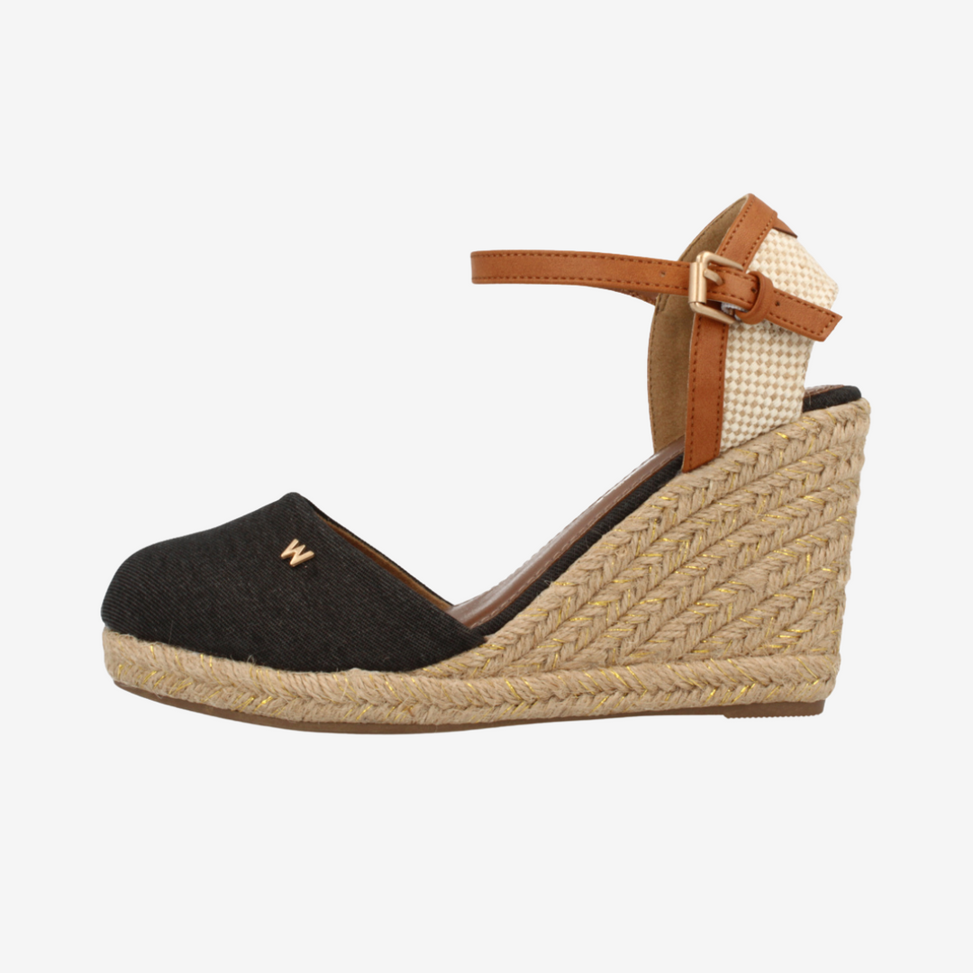 Wedge sandal with black upper and brown strap on a white background